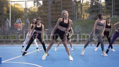 女子健身队与教练在公园的运动场上进行<strong>日间</strong>蹲式练习
